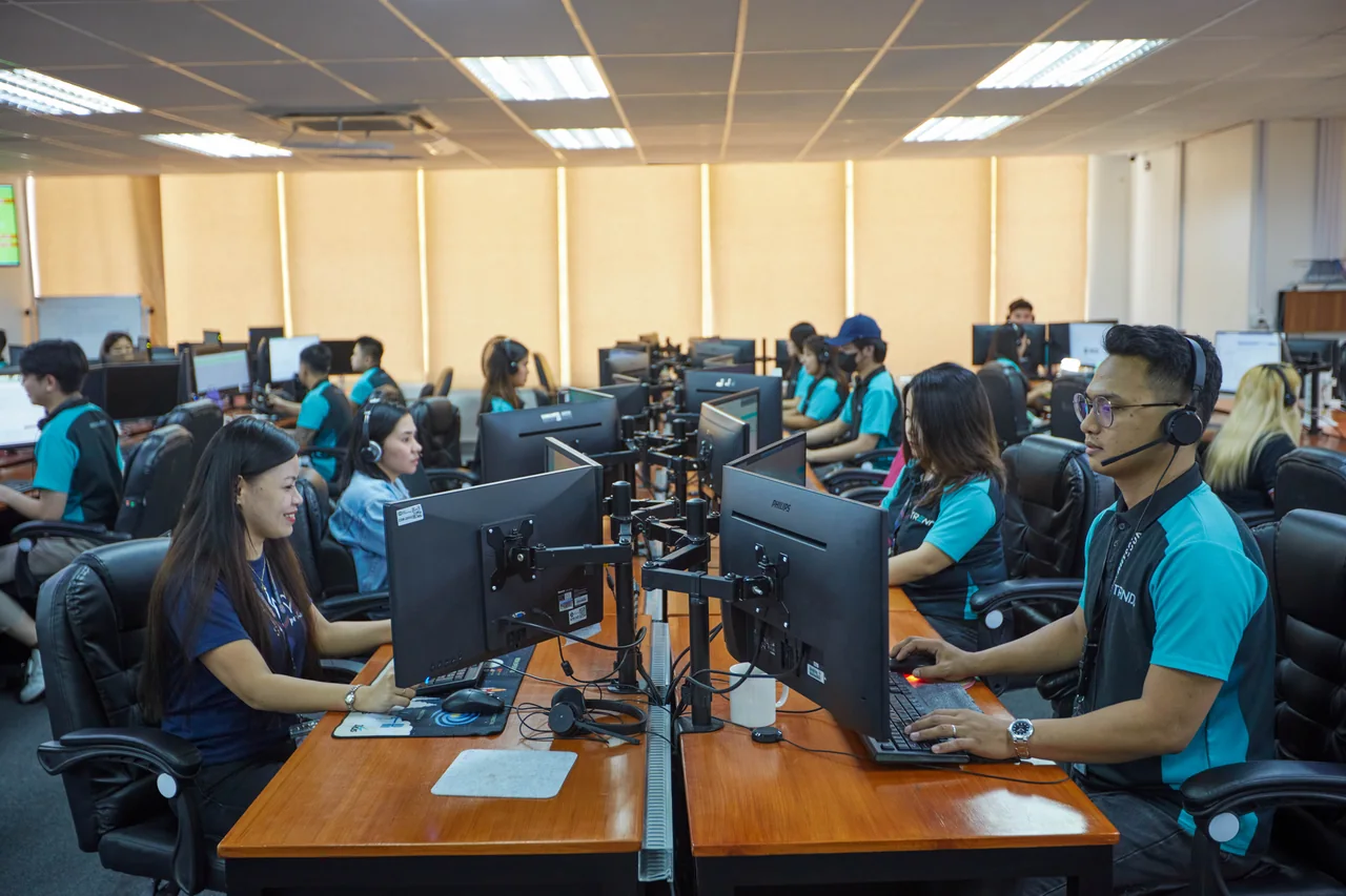 Back-End Developer outsourcing in the Philippines — headset-wearing colleagues at facing desks near office windows