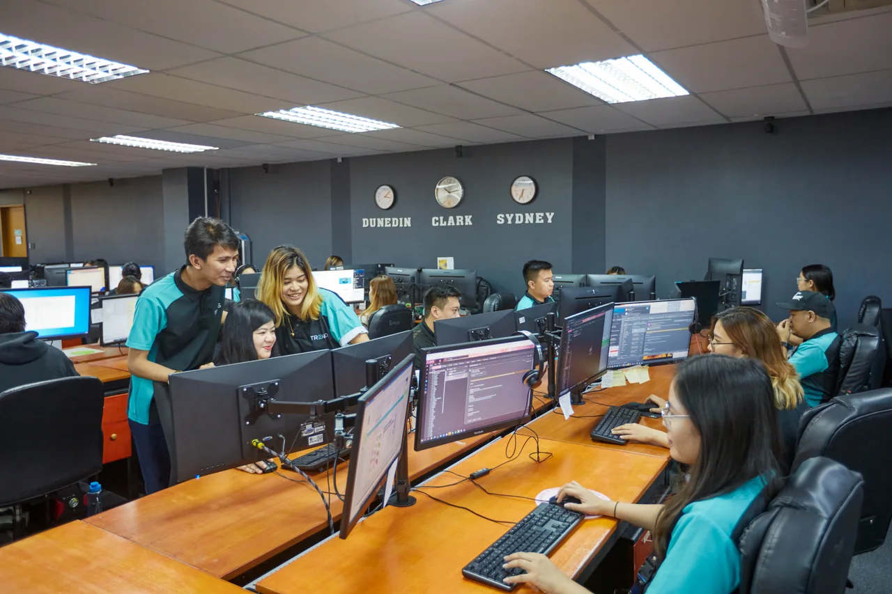 BPO contact center outsourcing in the Philippines — colleagues discussing work on a desktop computer in the open office