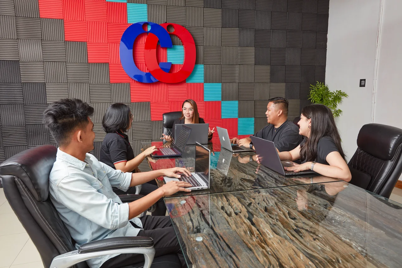 Case Manager outsourcing in the Philippines — five colleagues meeting around a long conference table with open laptops