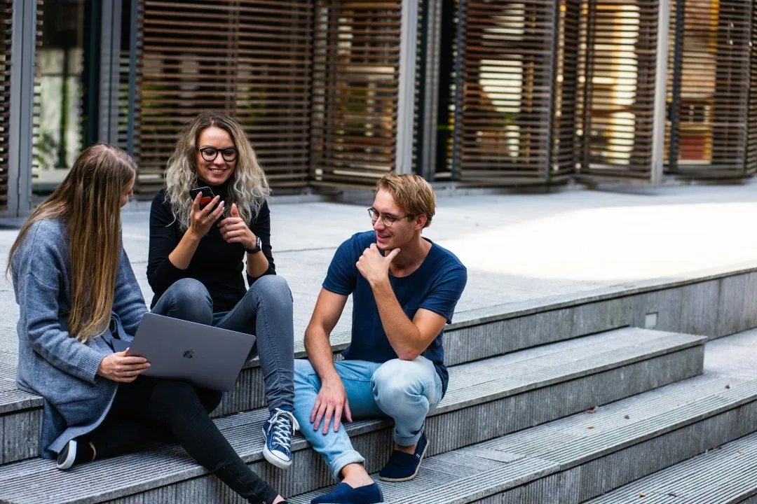 Three colleagues discussing work on outdoor steps
