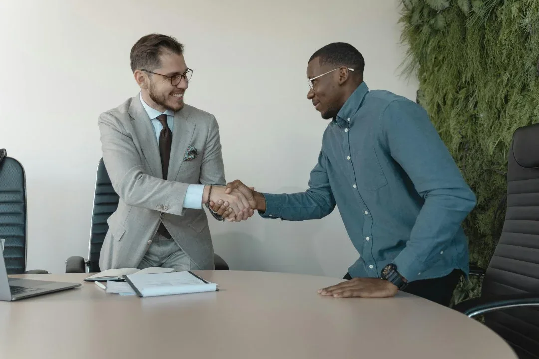 Two professionals shaking hands across a desk