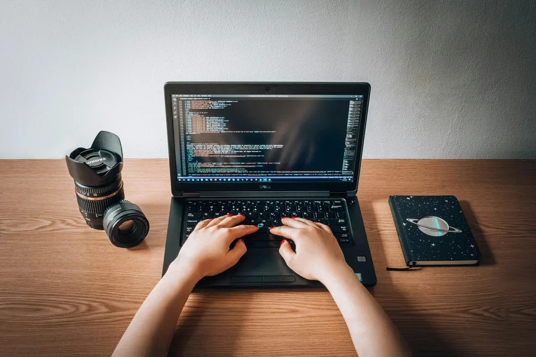 Person working on a laptop beside a camera