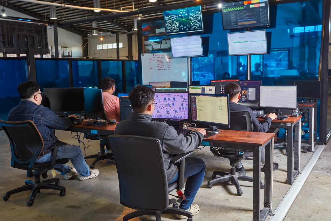 Content Writer outsourcing in the Philippines — colleagues working at desktop computers beneath wall-mounted office screens