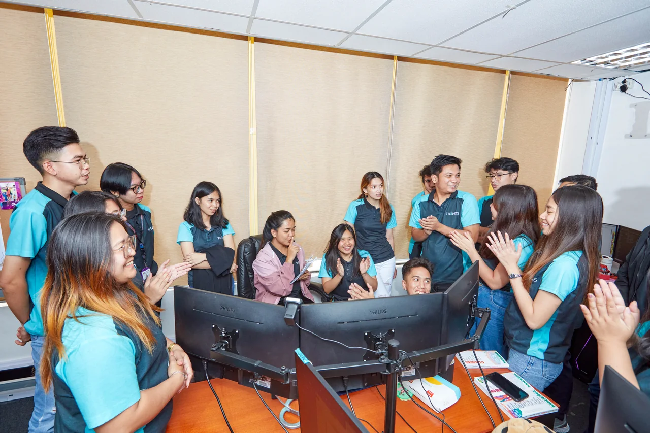 Full Stack Developer outsourcing in the Philippines — a group of colleagues talking and applauding beside office workstations