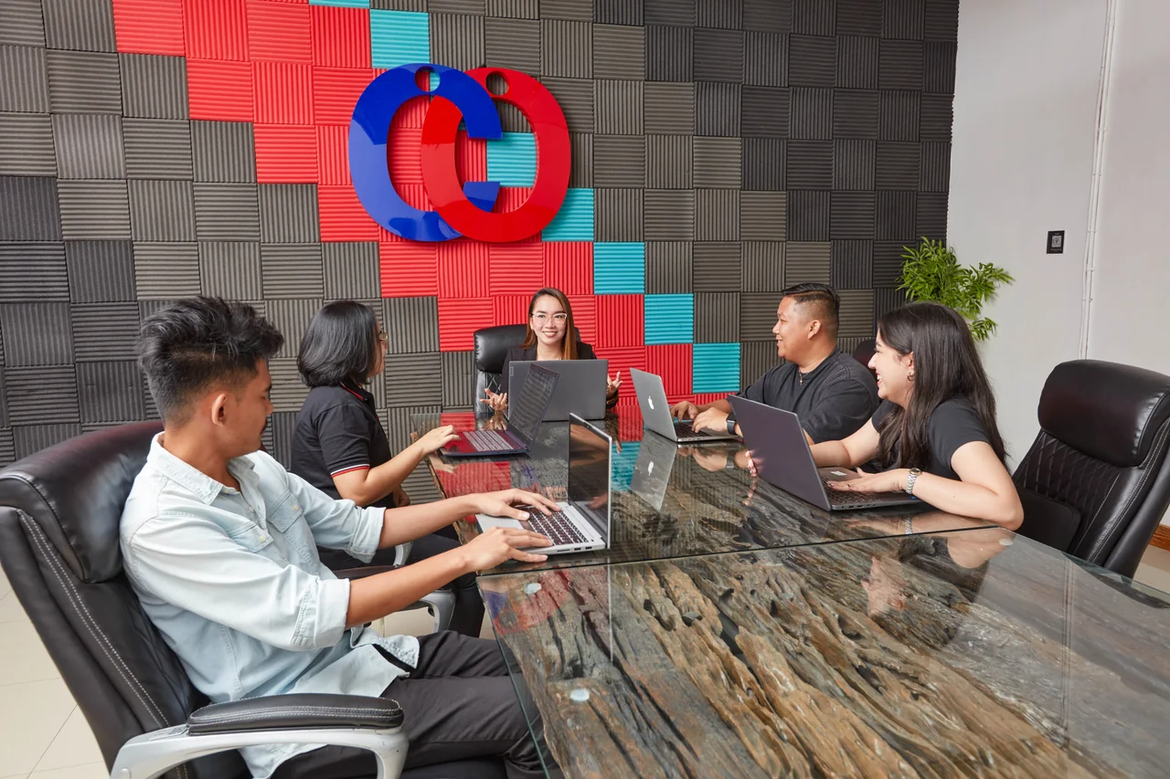 General Accountant outsourcing in the Philippines — colleagues meeting around a conference table with laptops in the branded meeting room
