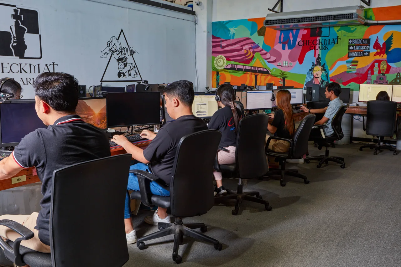 Graphic Designer outsourcing in the Philippines — side view of team members working at desktop computers in a mural-lined office