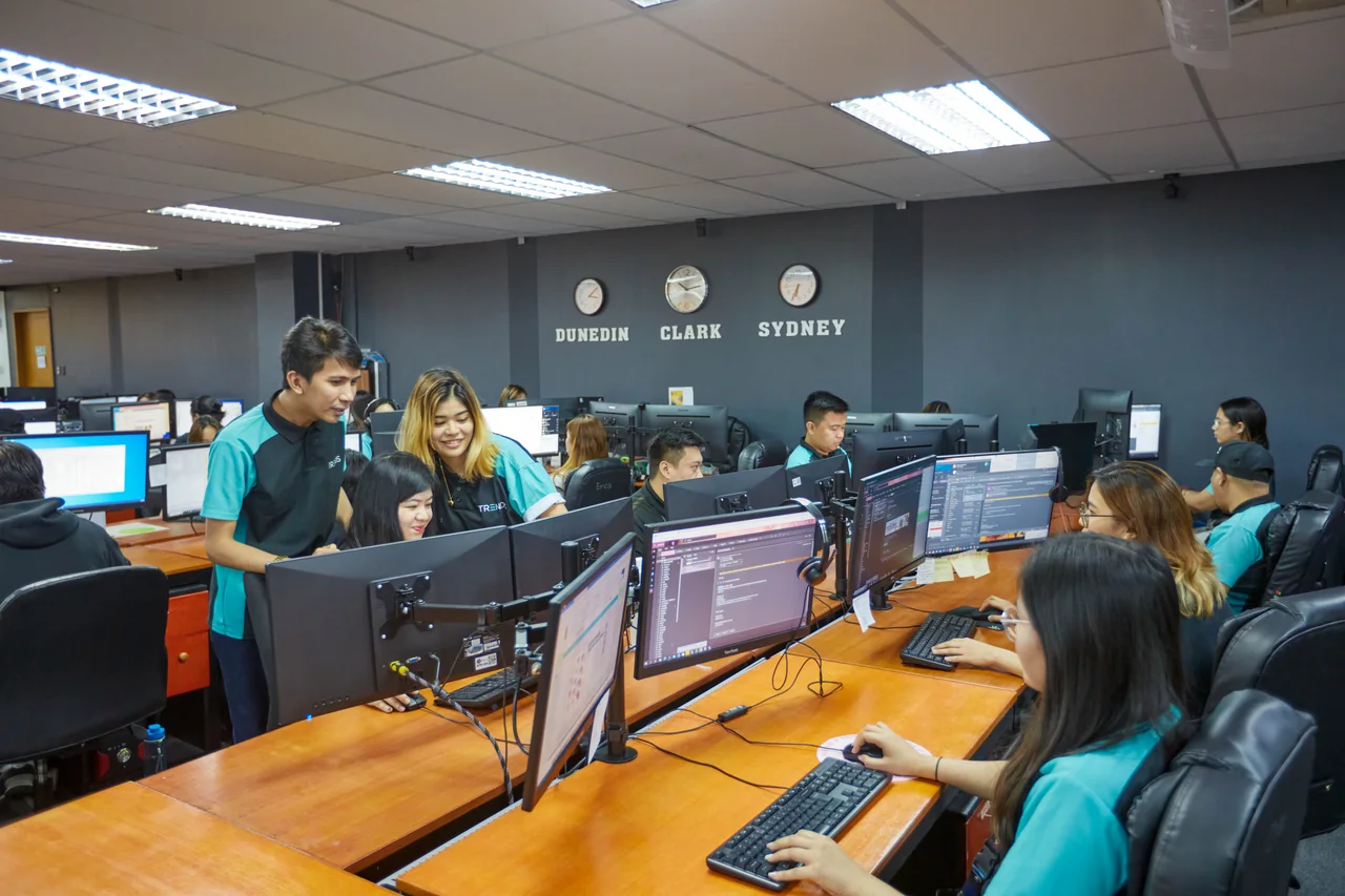 Quality Assurance Registered Nurse outsourcing in the Philippines — team members gathered around a colleague's desktop computer in the office