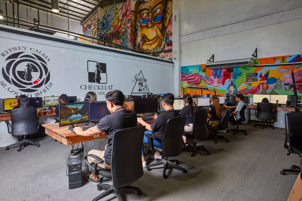 Software Development outsourcing in the Philippines — a row of colleagues working at computers beside a mural-covered wall